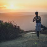 Woman doing yoga pose in front of sunrise