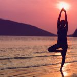 Woman doing yoga pose in front of a sunrise