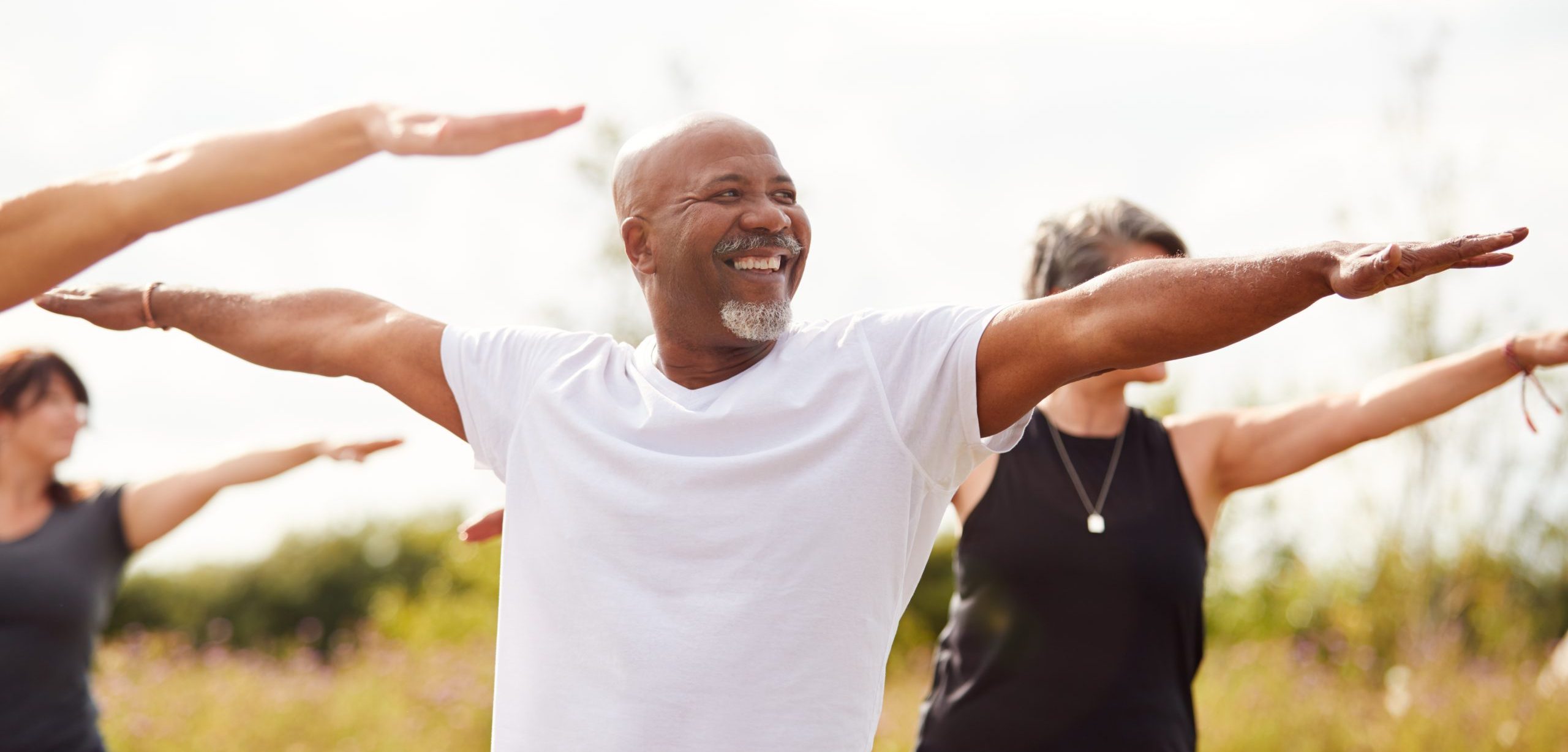 Group Of Mature Men And Women In Class At Outdoor Yoga Retreat