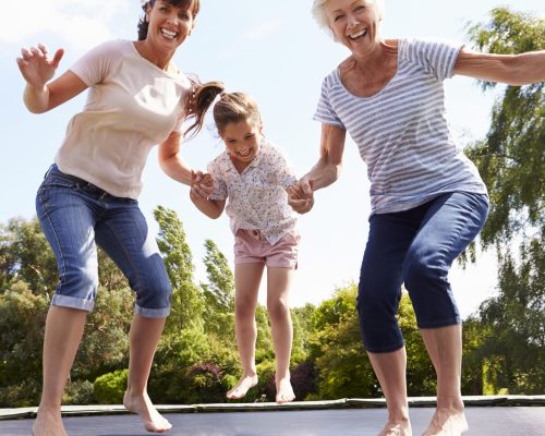 Grandmother,,Granddaughter,And,Mother,Bouncing,On,Trampoline