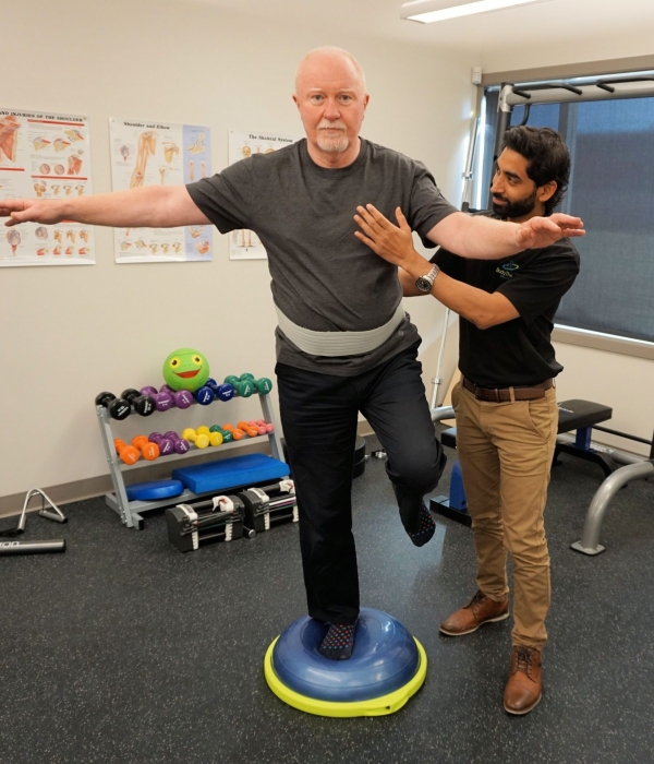 Standing on balance ball with one leg with help from a physiotherapist